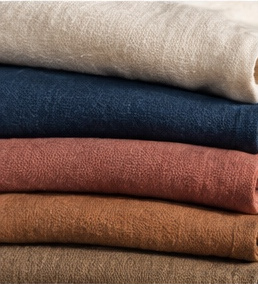 Folded fabrics stacked in raw cotton, indigo, madder and brown tones